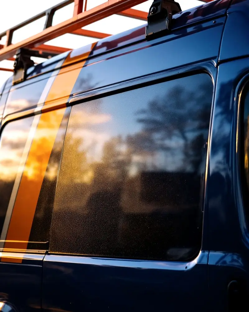 Navy van sliding door with an orange stripe and a ladder rack above